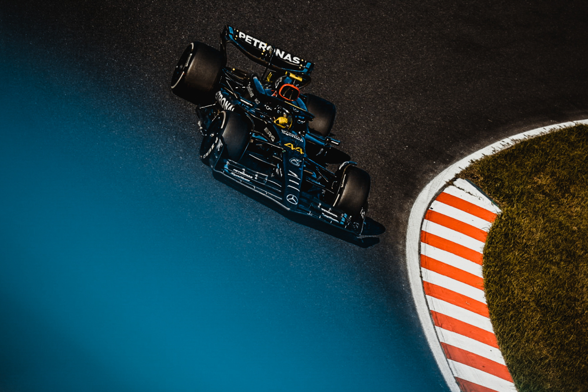 Formula 1 car from directly above, clipping an orange-and-white kerb