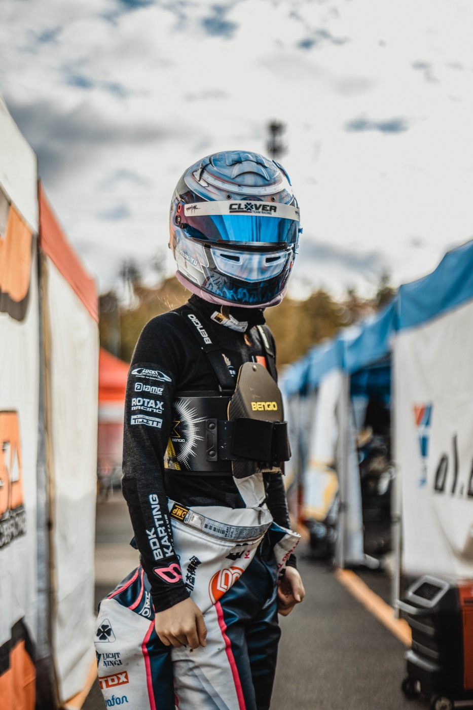 Driver portrait in the paddock lane, helmet on, visor mirrored